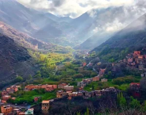 Picturesque mountain valley view of the Berber village of Imlil in the High Atlas Mountains of Morocco, featuring traditional earthen architecture surrounded by lush green terraced fields and dramatic peaks.