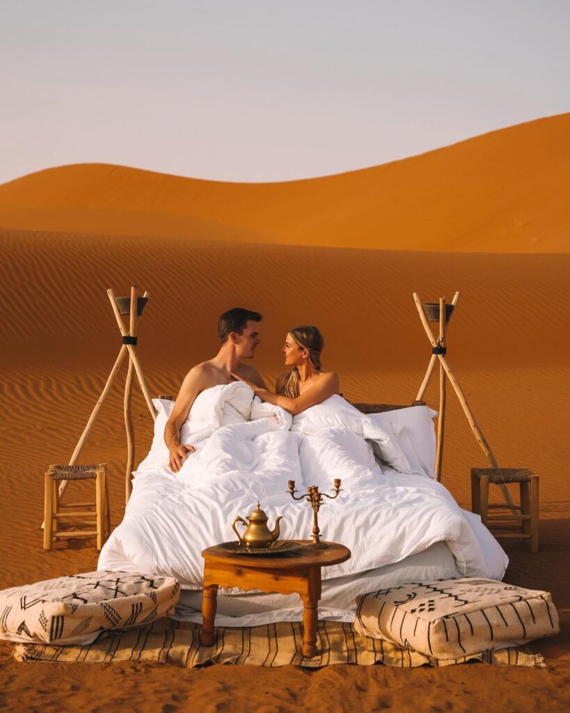 Couple watching sunset over the Sahara dunes, Morocco honeymoon