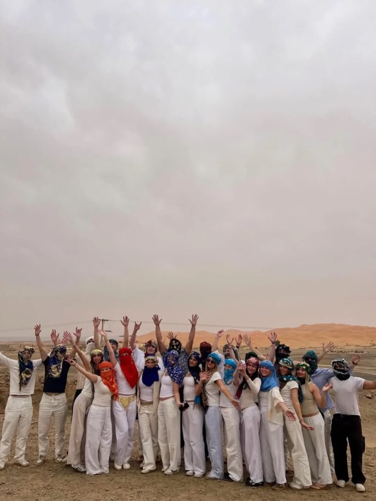 Student group celebrating on the Sahara dunes in Merzouga