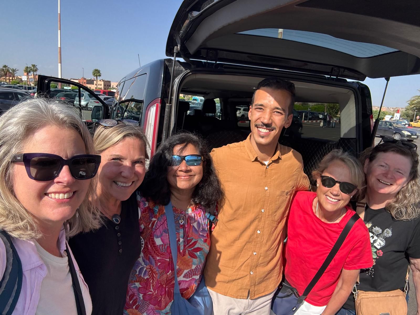 Happy travelers with their Navigate Morocco guide beside the private tour van