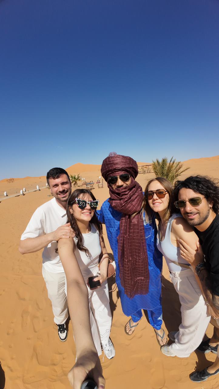 Desert guide in a turban with travelers on the Merzouga dunes