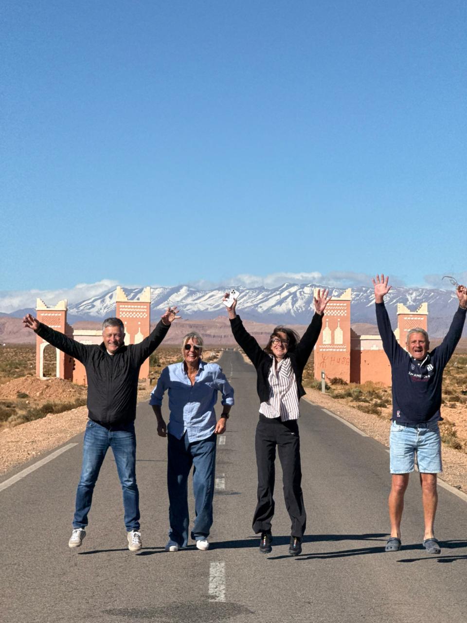 Travelers on the road near Ouarzazate with the snowy High Atlas behind