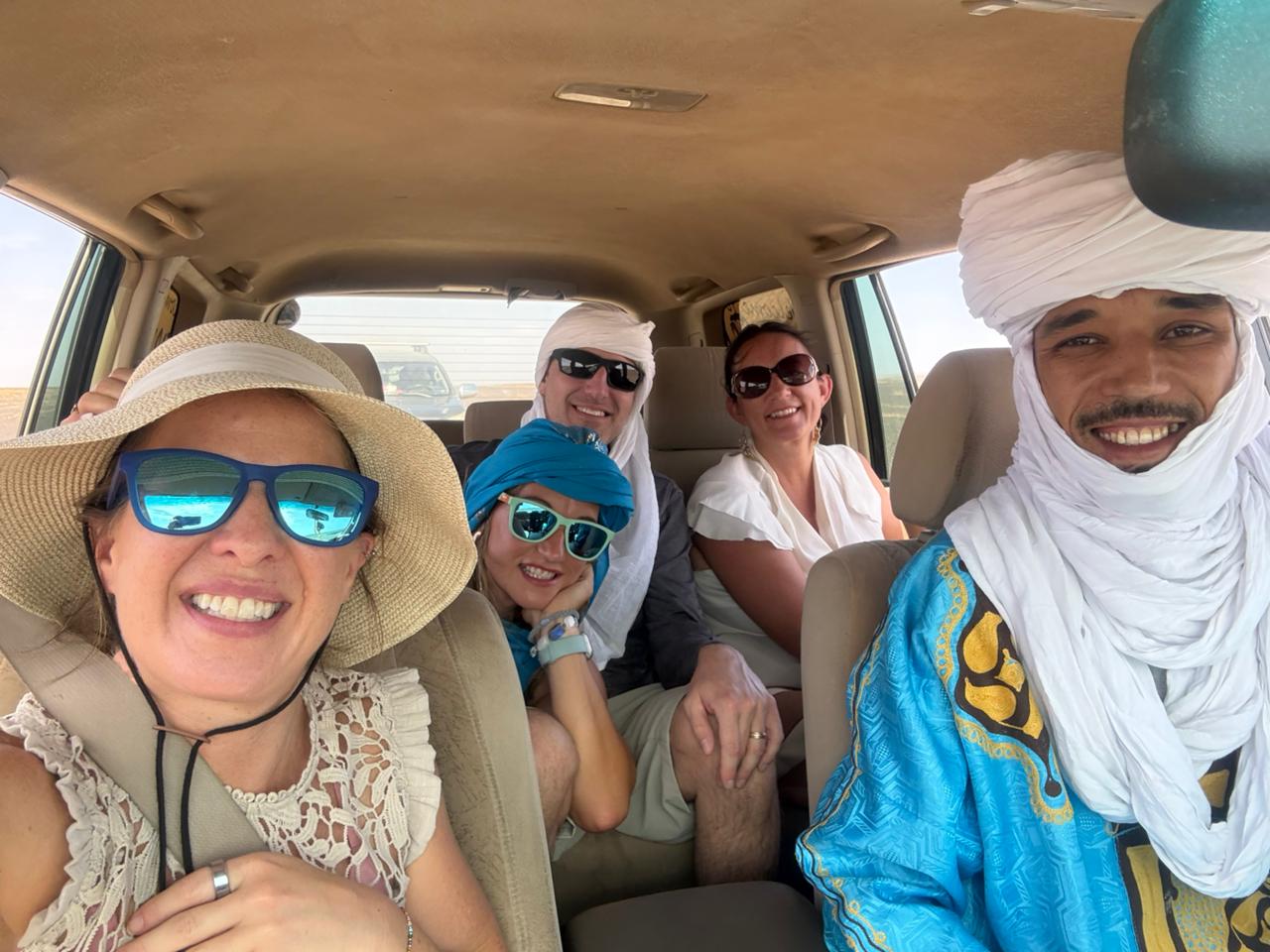 Desert driver-guide in a turban with travelers in the tour vehicle