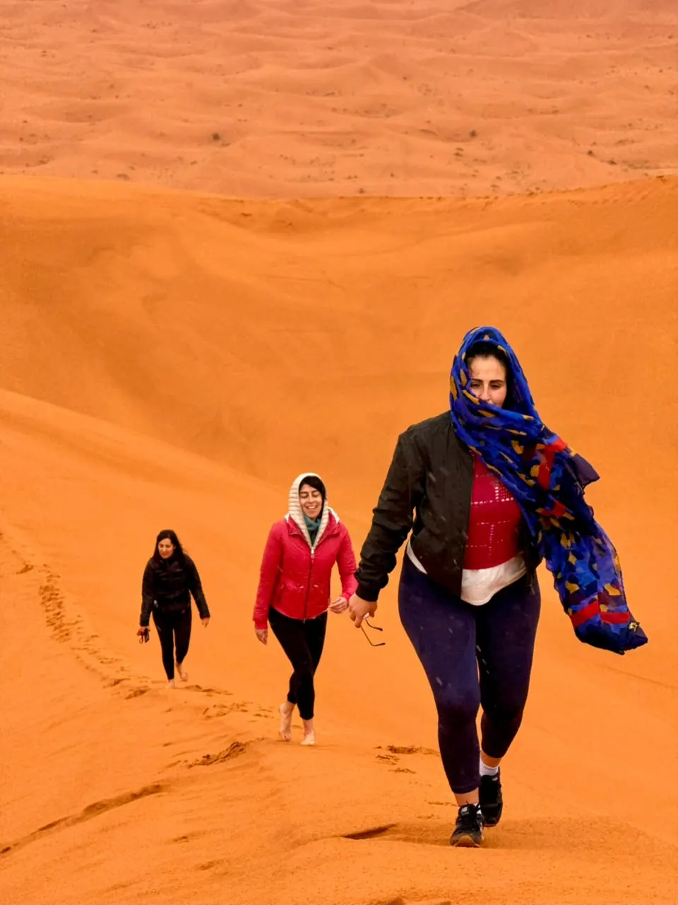 Travelers walking up the Erg Chebbi dunes
