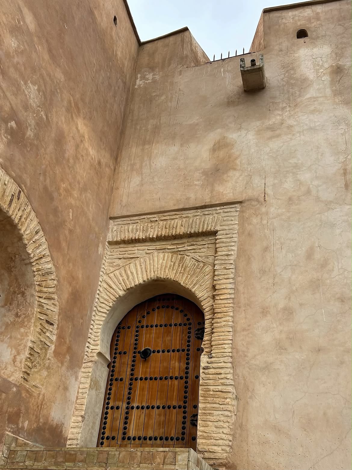 Old wooden door in an adobe wall in Fes