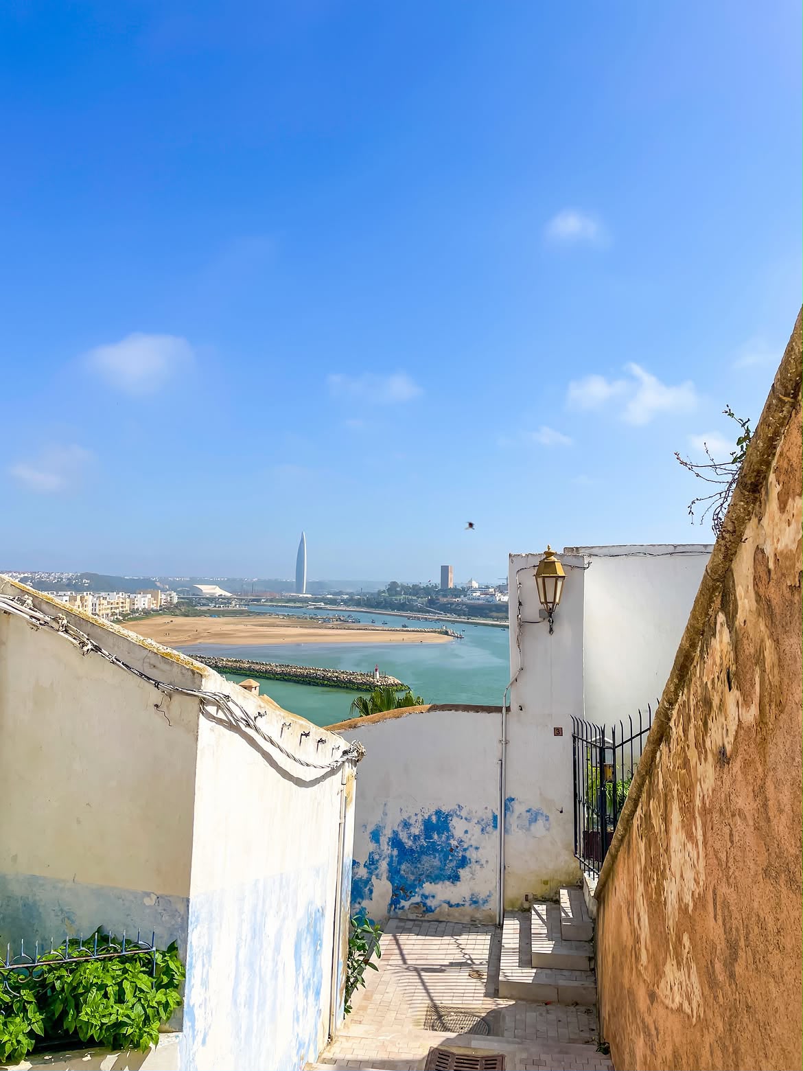 A white and blue lane in the Kasbah of the Udayas with a view of the river and sea in Rabat