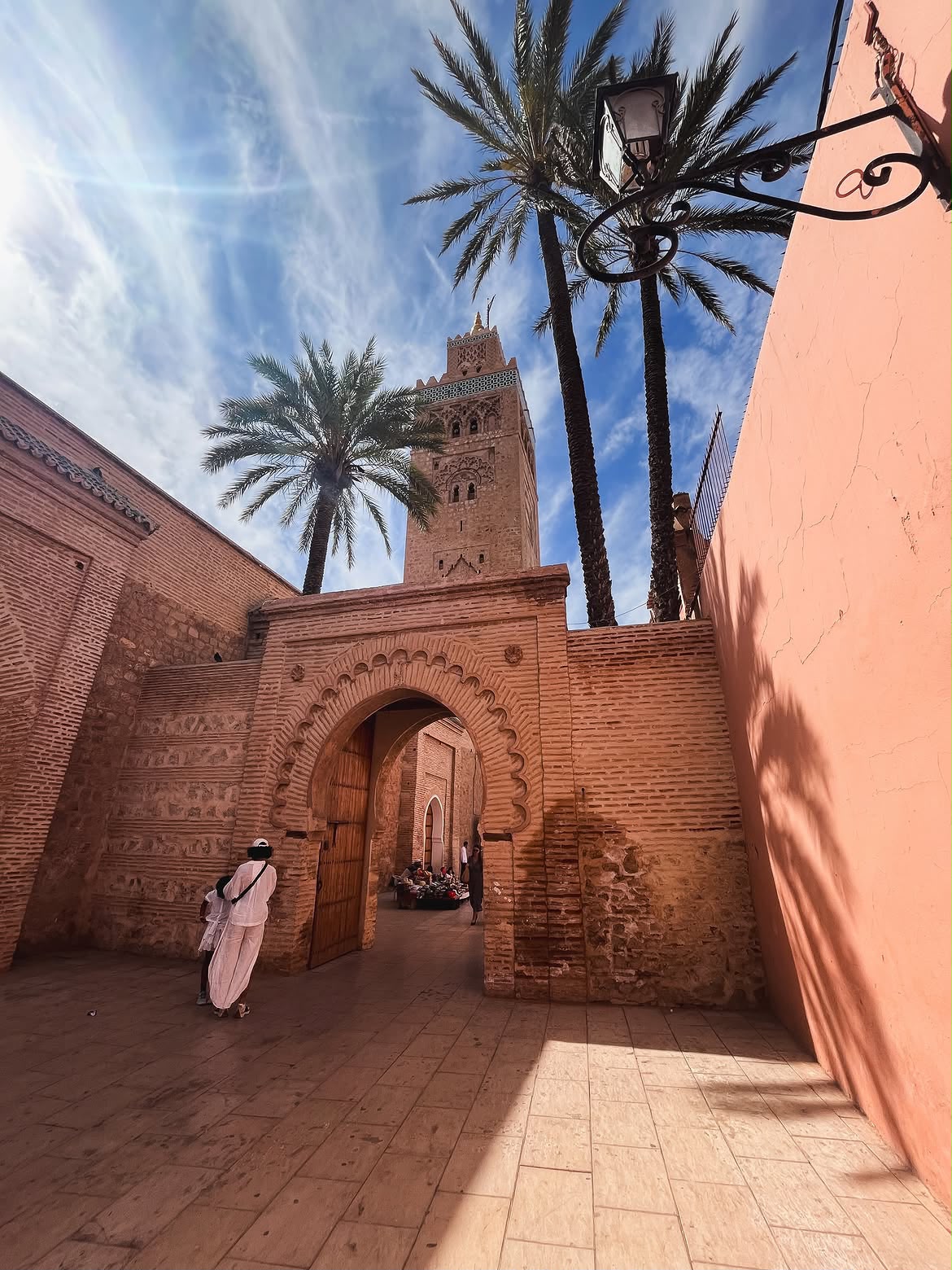 Callejón de Marrakech con palmeras y el alminar de la Kutubía al fondo