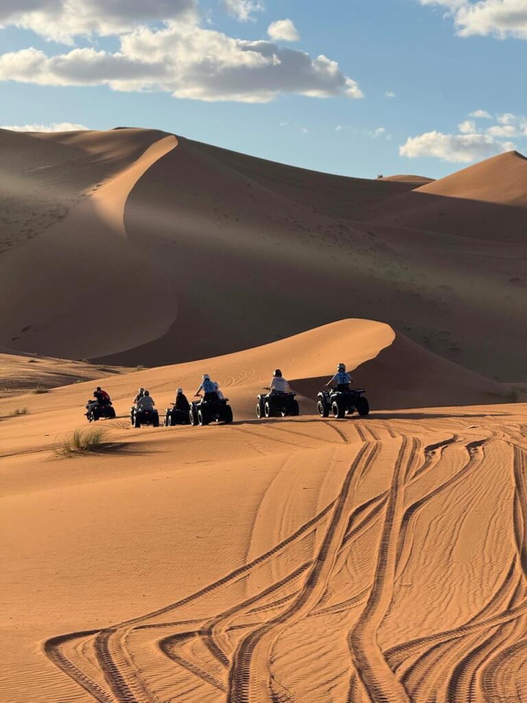 Group on quad bikes riding across the Erg Chebbi dunes, quad biking in Merzouga