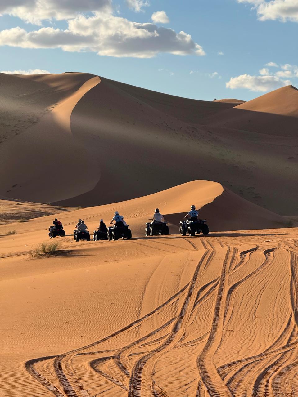 Group on quad bikes riding across the Erg Chebbi dunes in Merzouga