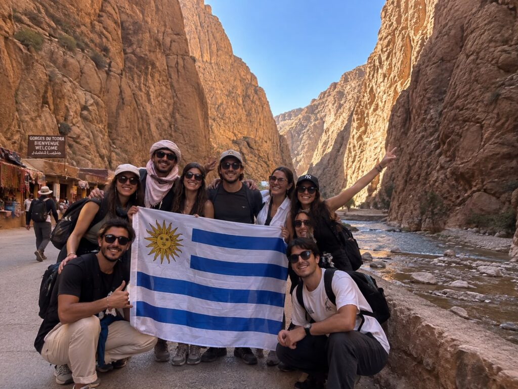 Grupo de viajeros uruguayos con la bandera de Uruguay en una garganta del sur de Marruecos
