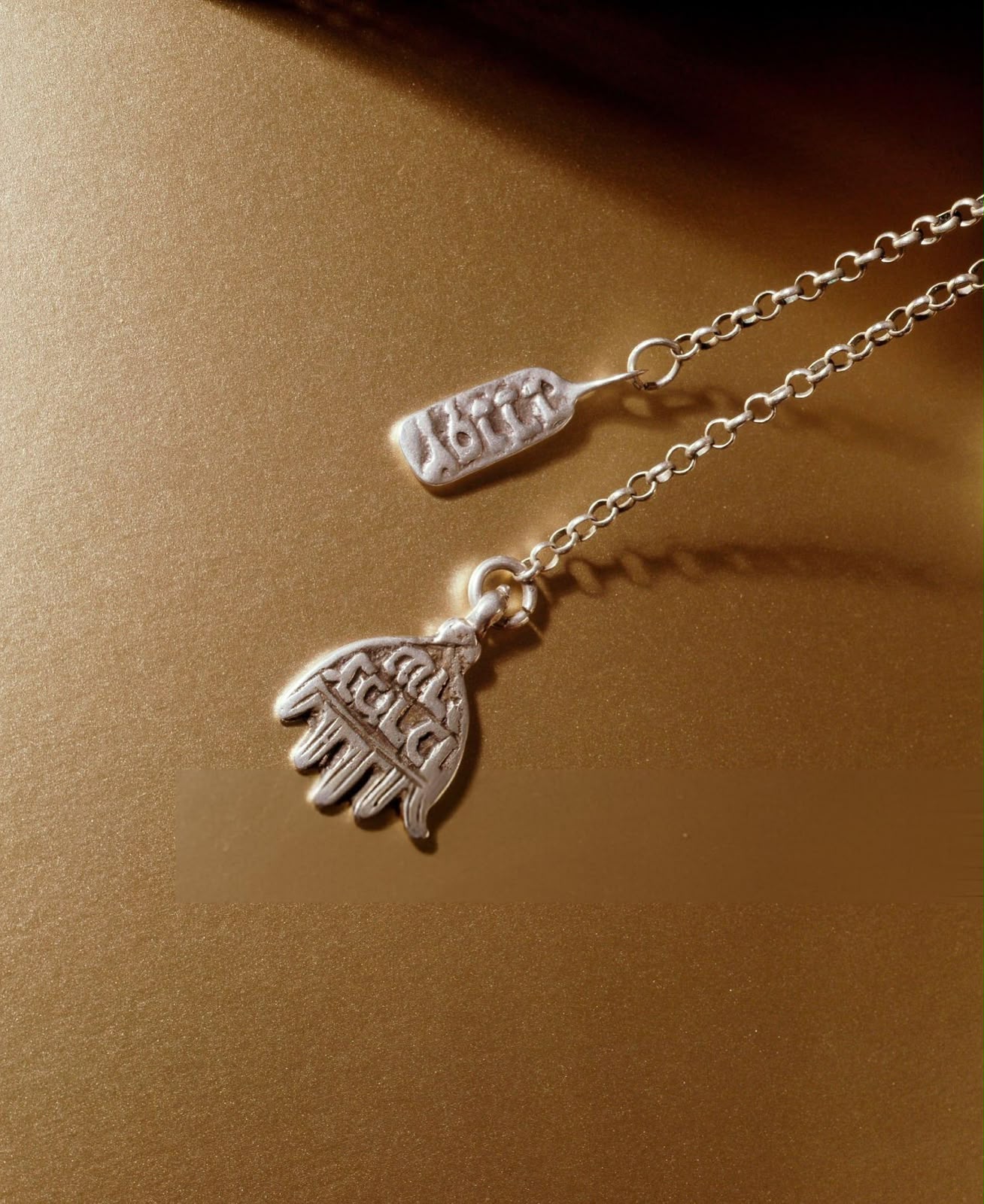 Silver Hand of Fatima pendant and a small tag on a chain