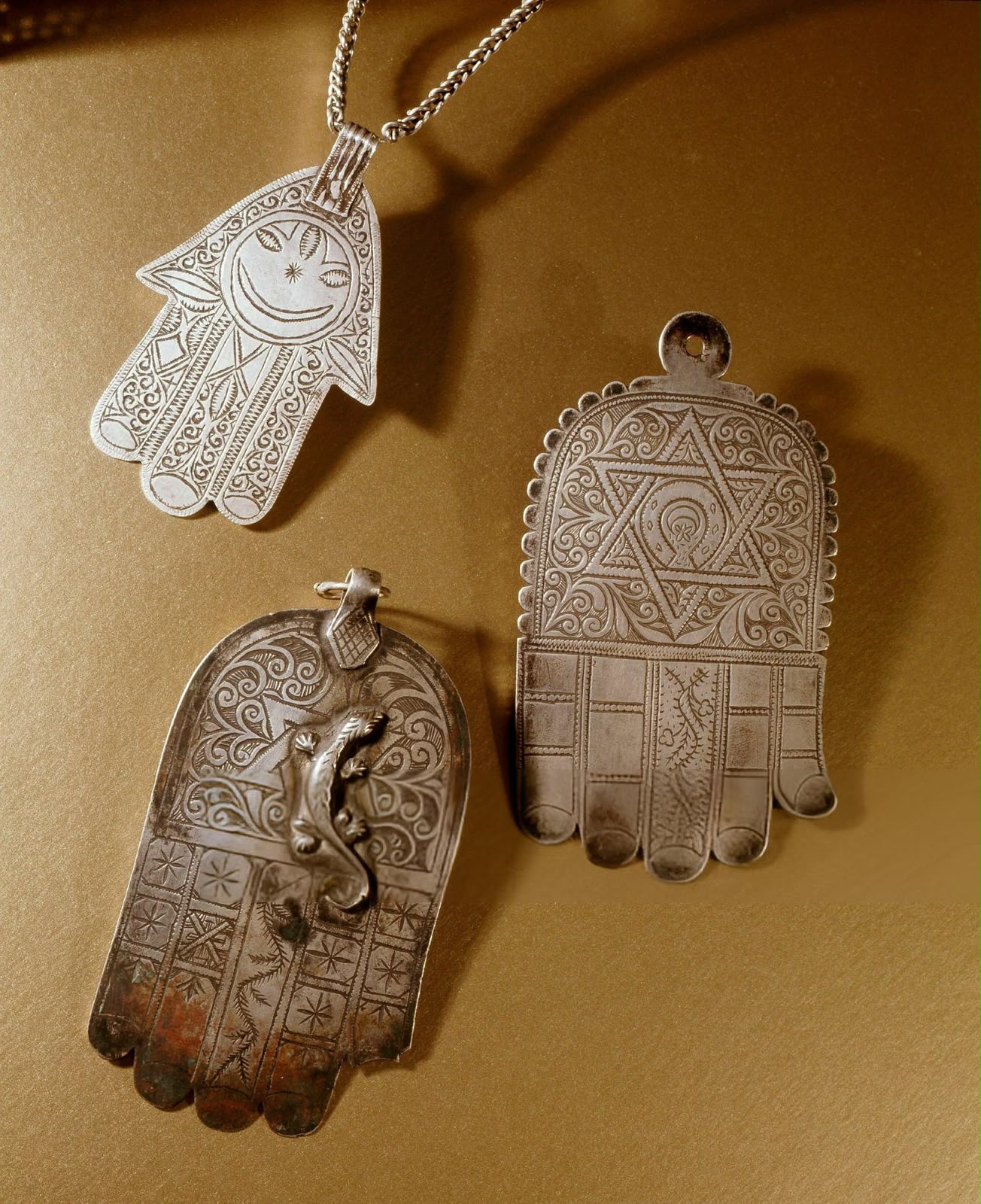 Three silver Hand of Fatima pendants, one engraved with a six-pointed star
