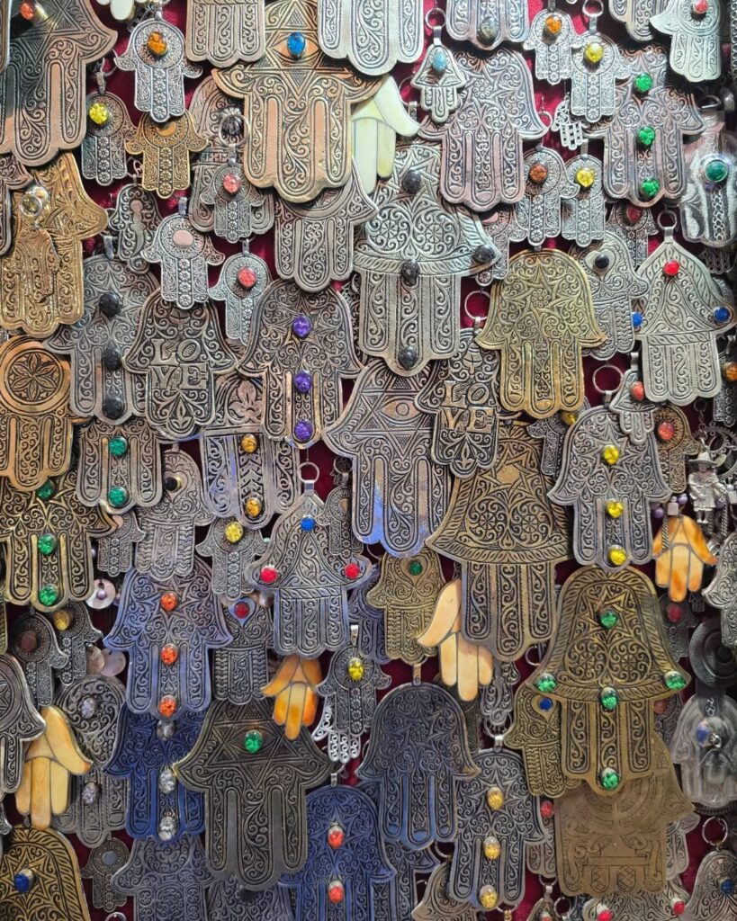 Wall of silver and metal Hand of Fatima pendants with colored stones