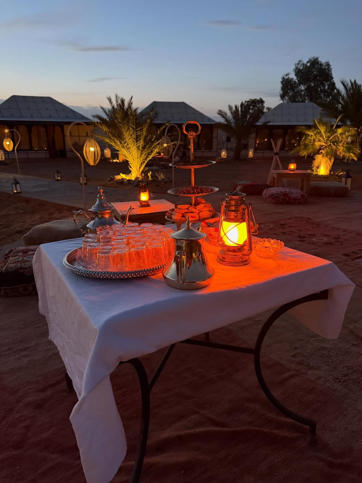 Mint tea set and lanterns on a table at a luxury desert camp in the Sahara at dusk