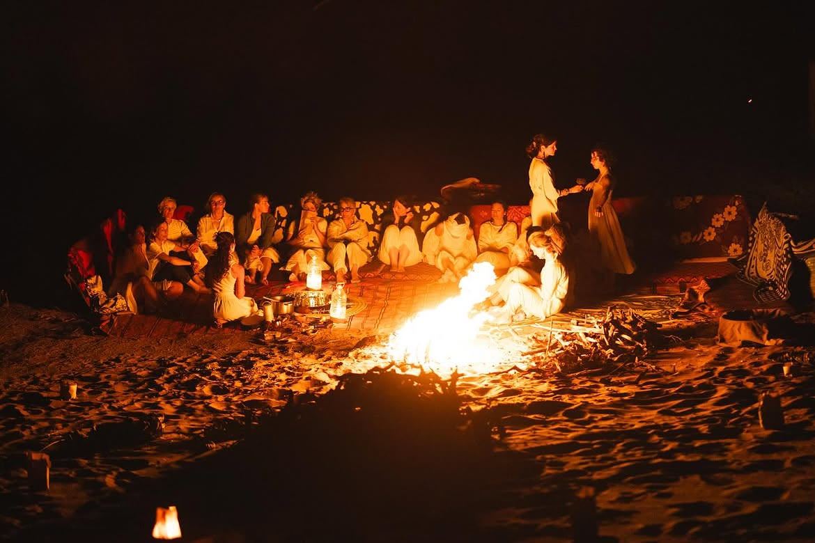 Travelers around the campfire at night at a Sahara desert camp