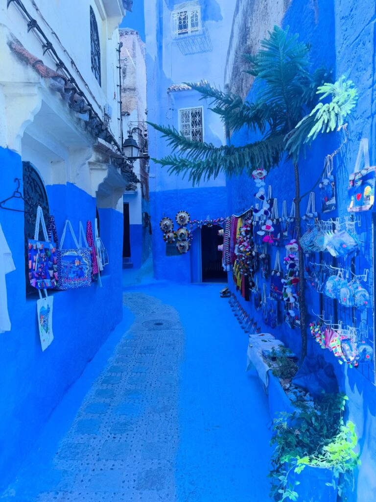 Callejón azul de Chefchaouen con bolsos y artesanías colgadas en la entrada de una tienda