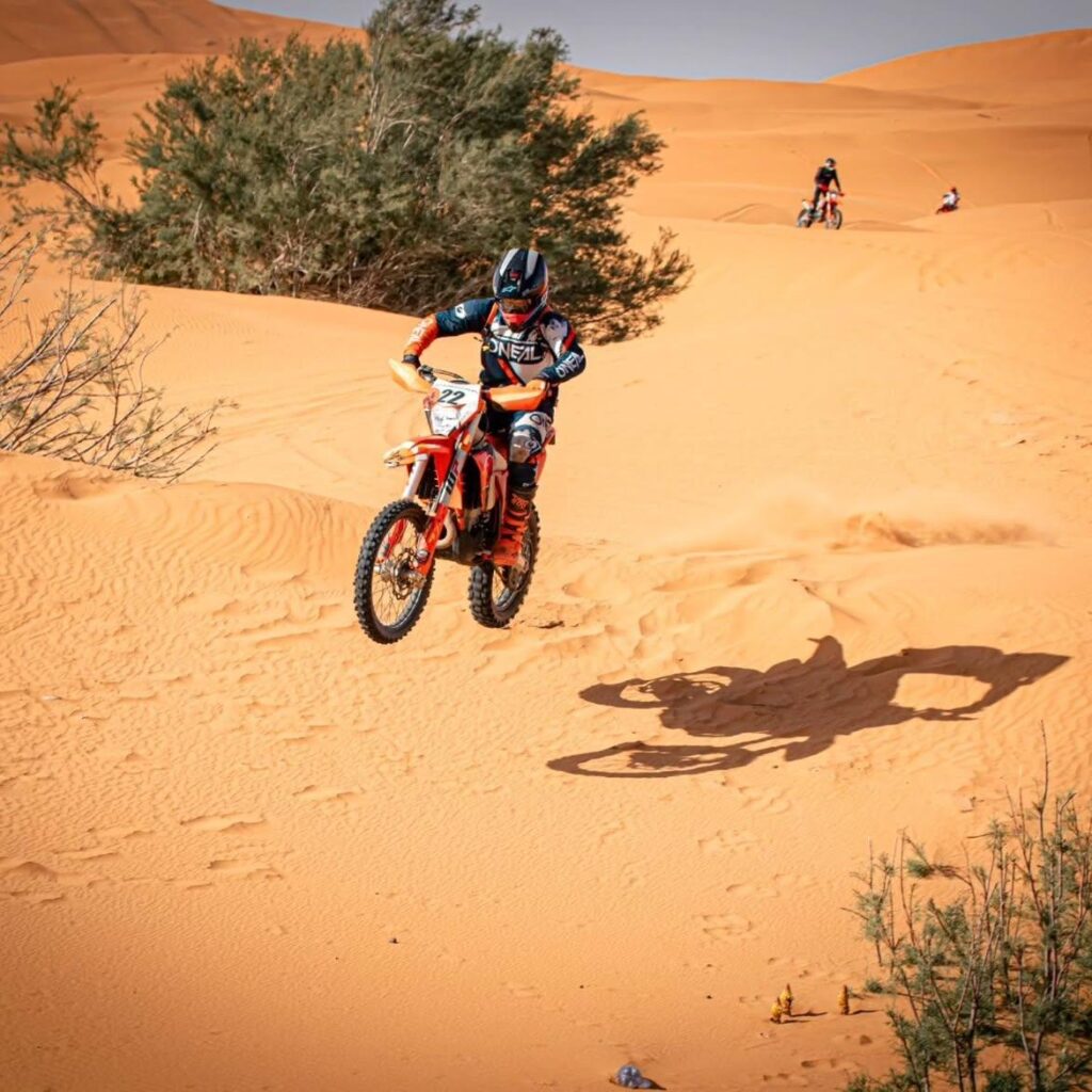 Dirt bike rider jumping over a sand dune in the Merzouga desert
