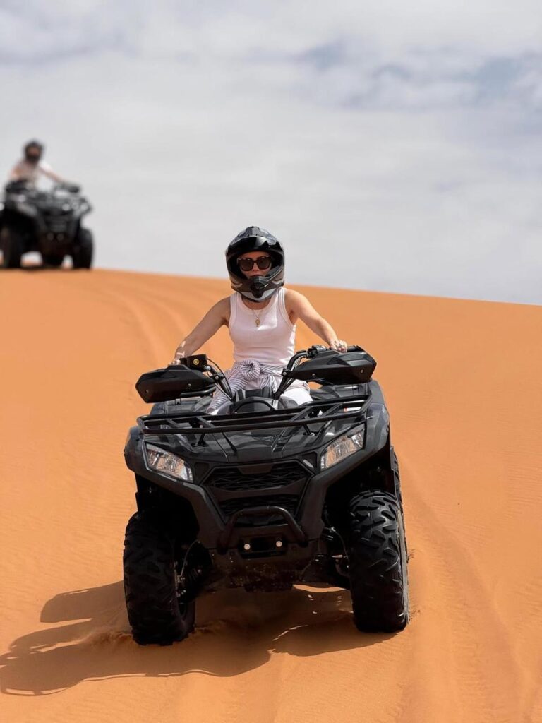 Rider in a helmet driving a quad bike over a dune in Merzouga