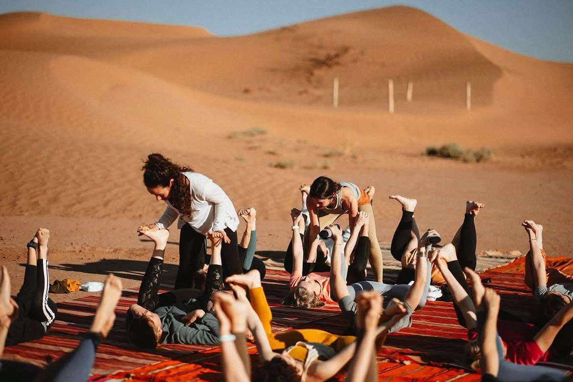 Group yoga class on rugs at a desert camp in the Sahara