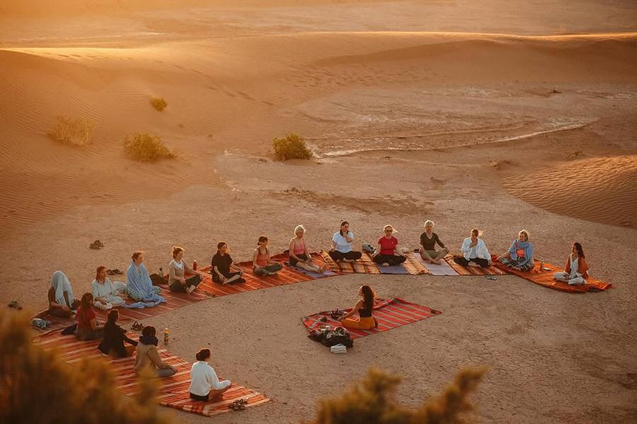 Group yoga in the Sahara near Merzouga on one of our wellness tours in Morocco