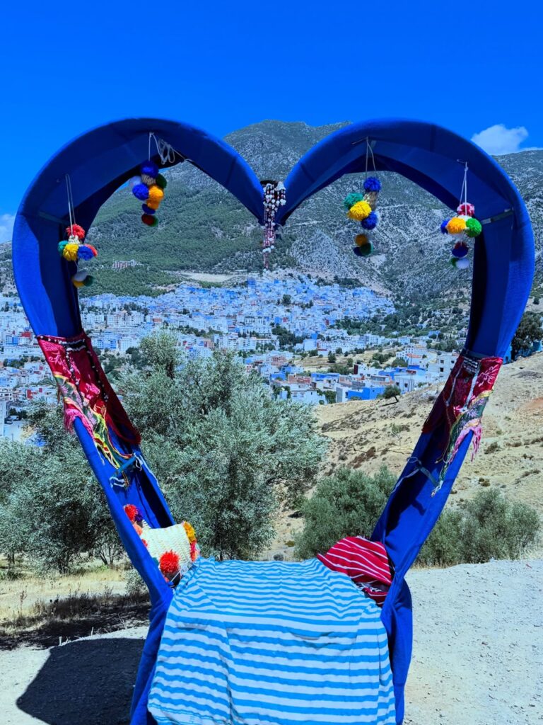 Marco azul en forma de corazón con vista a Chefchaouen desde un mirador