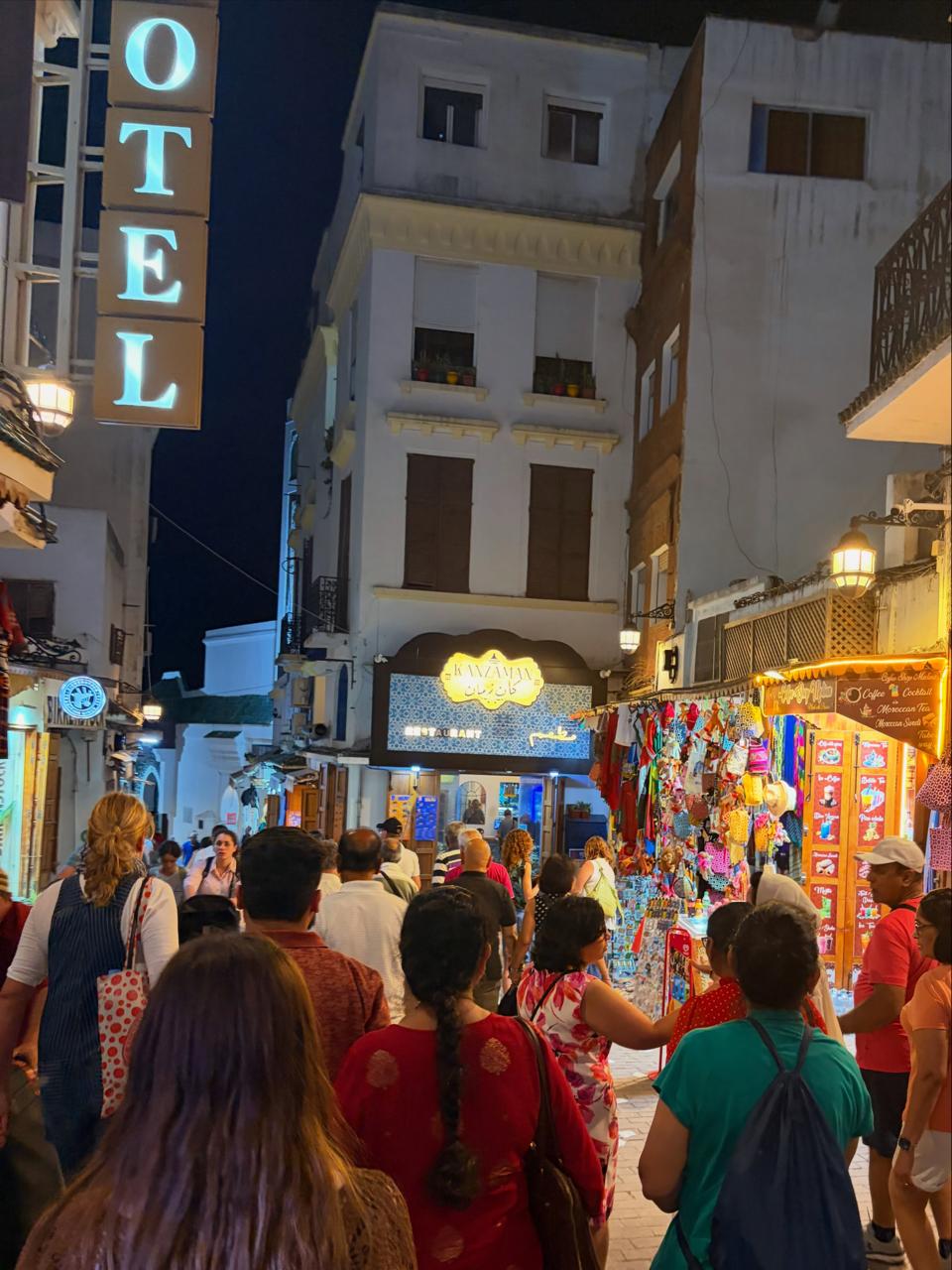 Crowded evening street with shop lights and a hotel sign