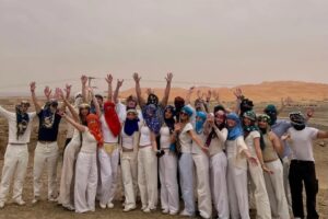 Student group in desert scarves celebrating in the Sahara dunes