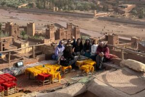 Travelers relaxing at a rooftop cafe overlooking Ait Ben Haddou