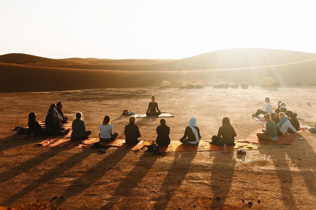Yoga group practicing at sunrise in the Sahara desert