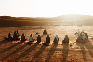 Yoga group practicing at sunrise in the Sahara desert